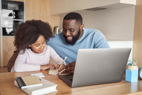 Happy african american family doing home task. Caring father help little daughter with school subject homework. Homeschooling conducted by parent, distant e-study and e-learning concept